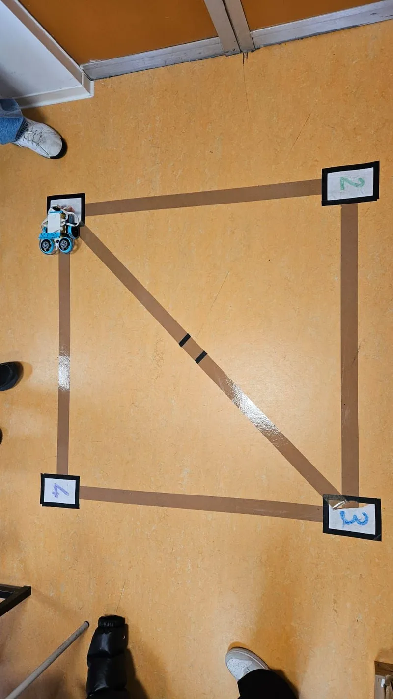 Piccolo robot su una griglia numerata costruita sul pavimento con nastro adesivo.